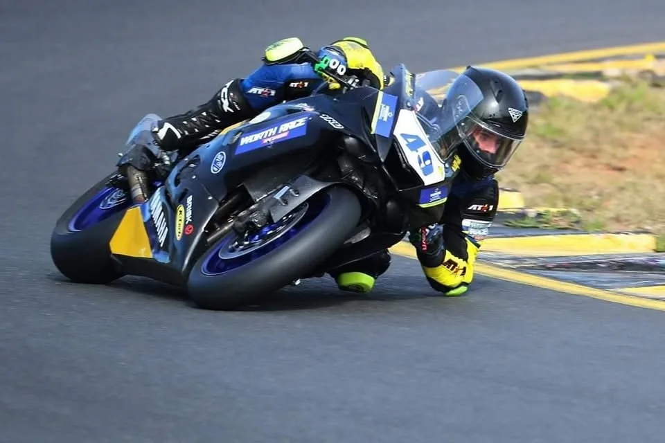 Jake Farnsworth elbow-down on track in his custom AT1 race suit